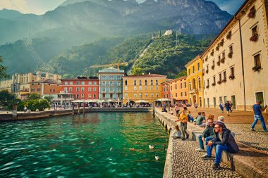 Riva del Garda, Lago di Garda, İtalya - 13 Ekim 2019: Garda Gölü 'nde yürüyüş yapan turistler, Riva del Garda' da dağlarla çevrili renkli bir sonbahar, Trentino Alto Adige bölgesi, Lago di garda, İtalya