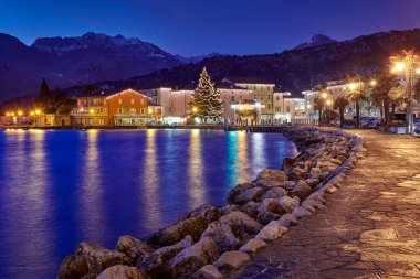 Şehir merkezini ve Torbole Caddesi 'ni süsleyen Noel ışıkları, gece güzel Torbole kasabası manzarası, Trento, İtalya