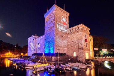 Riva del Garda, Lago di Garda, İtalya - 10 Aralık 2019: Şehir merkezini süsleyen Noel ışıkları ve Riva del Garda Caddesi, geceleri güzel Riva del Garda kasabasının manzarası, İtalya