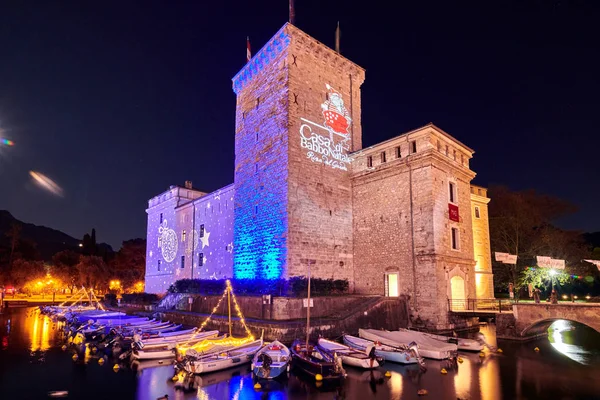 Riva del Garda, Lago di Garda, İtalya - 10 Aralık 2019: Şehir merkezini süsleyen Noel ışıkları ve Riva del Garda Caddesi, geceleri güzel Riva del Garda kasabasının manzarası, İtalya