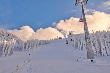 Kayak merkezindeki kırmızı teleferik, kayakçılar ve snowboardcular kış tatil beldesi Whit Ormanı 'ndaki kayak yamaçlarının keyfini çıkarıyorlar.