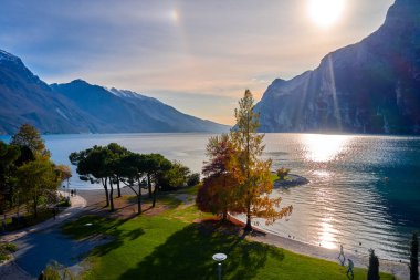 Riva del Garda 'da güzel ve renkli bir sonbahar, muhteşem Garda Gölü' nün panoraması sonbahar zamanı dağlarla çevrili.