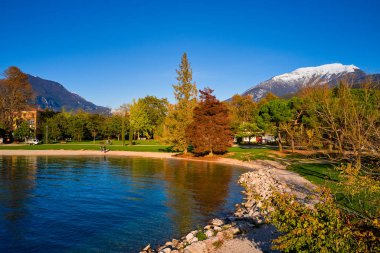 Riva del Garda 'da güzel ve renkli bir sonbahar, muhteşem Garda Gölü' nün panoraması sonbahar zamanı dağlarla çevrili.
