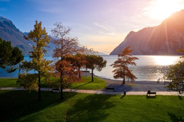 Riva del Garda 'da güzel ve renkli bir sonbahar, muhteşem Garda Gölü' nün panoraması sonbahar zamanı dağlarla çevrili.
