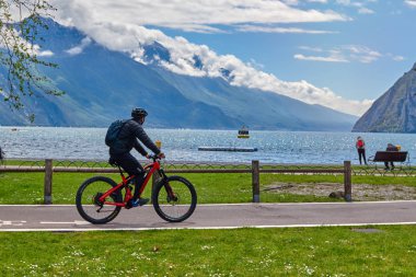 Riva del Garda, Lago di Garda, İtalya -09 Mayıs 2019: Garda Gölü kıyısında bisiklet süren turistler, Trentino Alto Adige bölgesi, İtalya