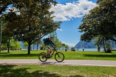 Riva del Garda, Lago di Garda, İtalya -09 Mayıs 2019: Garda Gölü kıyısında bisiklet süren turistler, Trentino Alto Adige bölgesi, İtalya