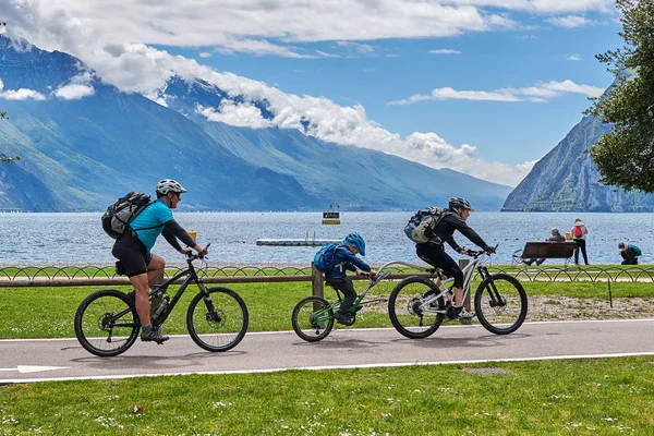 Riva del Garda, Lago di Garda, İtalya -09 Mayıs 2019: Garda Gölü kıyısında bisiklet süren turistler, Trentino Alto Adige bölgesi, İtalya