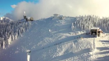 Karpatlar 'ın dağlarındaki muhteşem kayak yamaçlarının üzerinden uçuş, karla kaplı kayak yamacı beyaz orman, Transilvanya' da kayak merkezi,