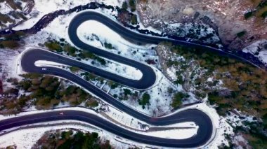 Kayalık dağ ormanlarındaki bir yılanın insansız hava aracı görüntüsü, Bicaz vadisi kış mevsiminde dolambaçlı yol ile, Cheile Bicazului, Romanya