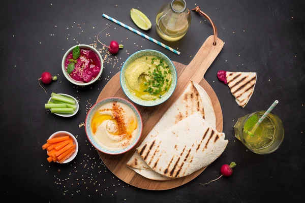 Vários mergulhos coloridos vegetarianos com pão pita — Fotografia de Stock