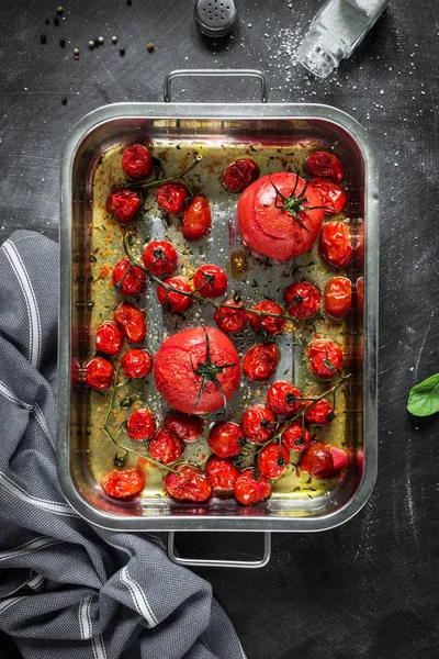 Tomates al horno en un plato tostador de metal en negro — Foto de Stock