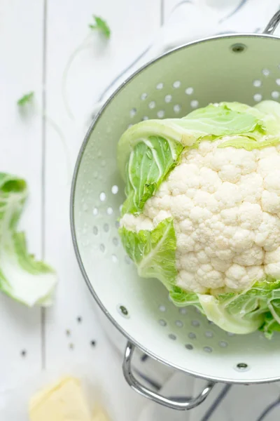 Fresh wet raw cauliflower in a strainer on white rustic wood — Stock Photo, Image