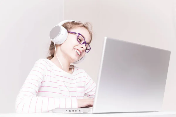 Happy child girl (kid) in headphones using laptop computer — Stock Photo, Image