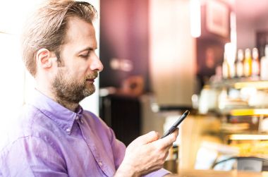 Kafede bir cep telefonu (smartphone) bakarak adam