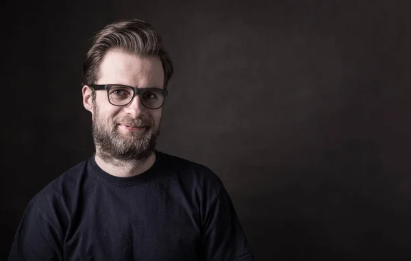 Dark moody portrait of happy caucasian man in glasses — Stock Photo, Image