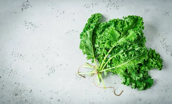 Fresh wet green kale leaves bunch on grey background — Stock Photo, Image
