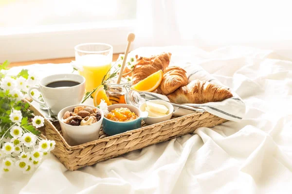 Bandeja de mimbre con desayuno continental en sábanas blancas —  Fotos de Stock
