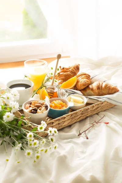 Wicker tray with continental breakfast on white bed sheets — Stock Photo, Image