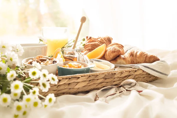 Korbtablett mit kontinentalem Frühstück auf weißen Bettwäsche — Stockfoto