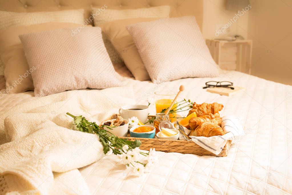Continental breakfast on bed in elegant bedroom interior