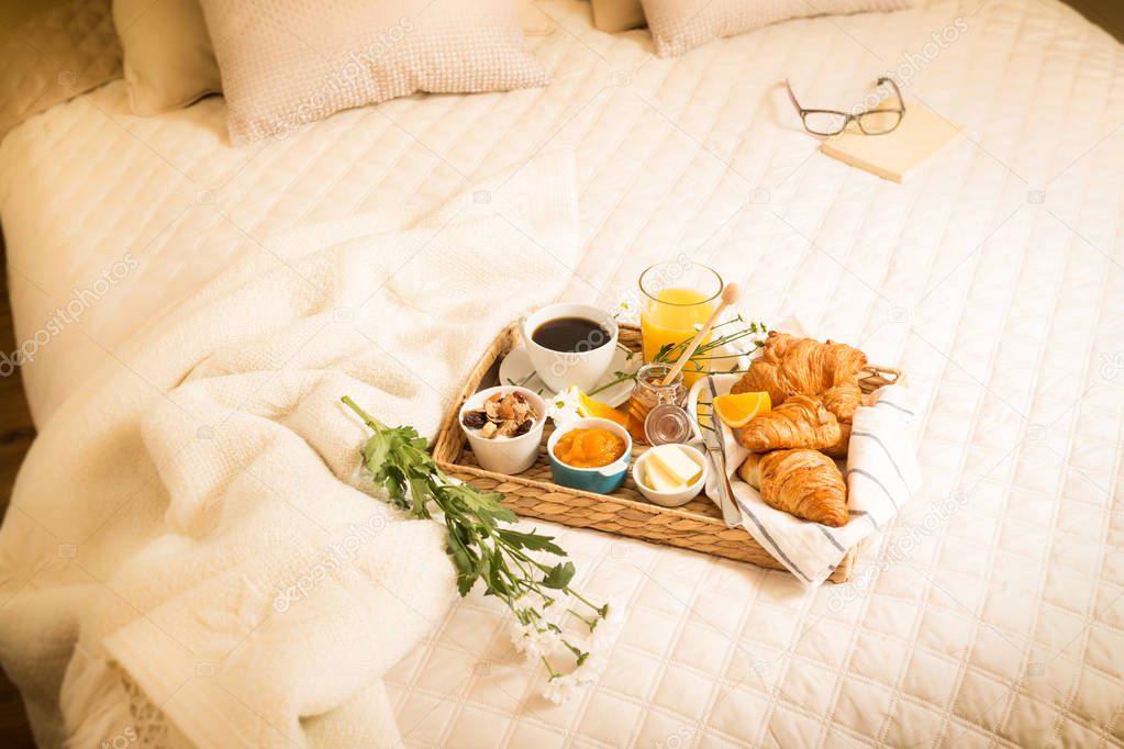 Continental breakfast on bed in elegant bedroom interior