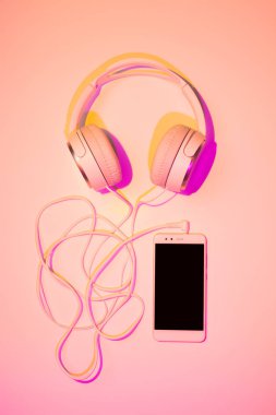 Hareket eden telefon (akıllı telefon) ve pembe kulaklıktan
