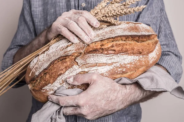 Rustykalne chrupiący bochenek chleba w ręce mężczyzny baker — Zdjęcie stockowe