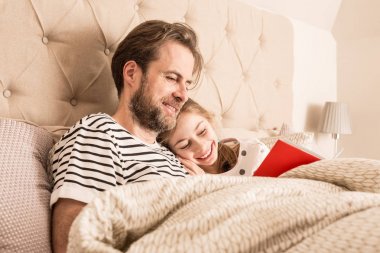 Baba ve kızı bir yatakta kitap okuma