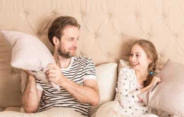 Mutlu baba ve kız yastık sahip bir yatakta mücadele