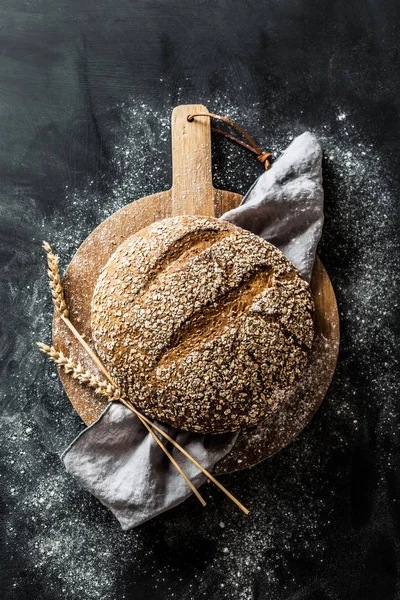 Panadería - hogaza redonda de pan rústico sobre fondo negro — Foto de Stock