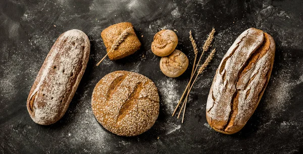 Αρτοποιείο - ρουστίκ κακότροπος καρβέλια ψωμί και ψωμάκια σε μαύρο — Φωτογραφία Αρχείου