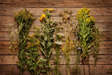 Yazın sonlarına doğru doğal çayır çiçekleri ve yukarıdan eski ahşap arka plandaki bitkiler. Doğa elementlerinin toplanması - rustik biçim.