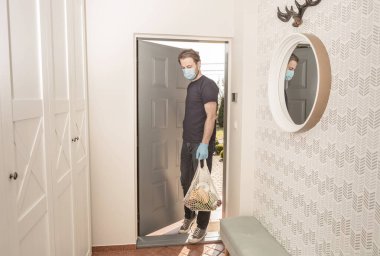 Tehlikeli virüs ya da bakteri salgını (cerrahi yüz maskesi ve tek kullanımlık eldivenlerle korunurken), insan marketten alışveriş yaptıktan sonra eve dönüyor).