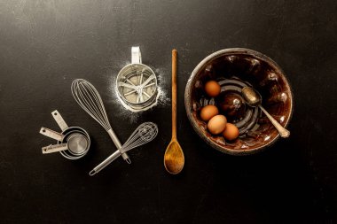 Eski seramik demet kek kalıbı ve siyah karatahta arka planda mutfak aletleri. Yukarıdan yakalanan pişirme araçları koleksiyonu (üst görünüm, düz görünüm). Boş kopya (metin) alanına sahip düzen.