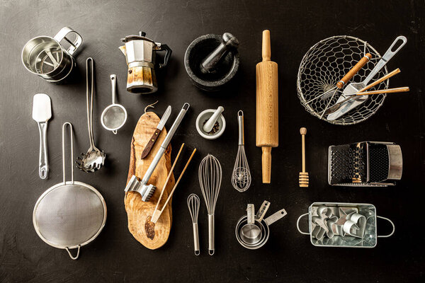 Kitchen utensils (cooking tools) on black chalkboard background. Kitchenware collection captured from above (top view, flat lay).