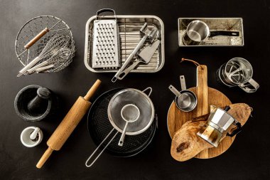 Siyah karatahta arka planında mutfak aletleri (pişirme aletleri). Yukarıdan alınan mutfak gereçleri koleksiyonu (üst görünüm, düz konum).