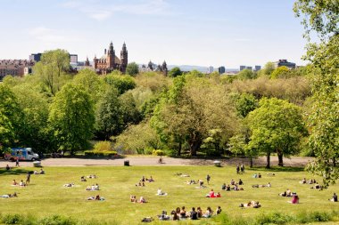 Gençler, Glasgow Üniversitesi öğrencileri Kelvingrove Art Gallery ve müze içinde belgili tanımlık geçmiş Kelvingrove park, çimenler sıcak güneşli bir günde zevk