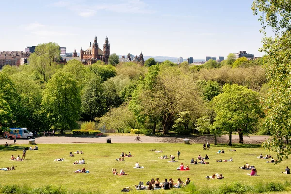 Gençler, Glasgow Üniversitesi öğrencileri Kelvingrove Art Gallery ve müze içinde belgili tanımlık geçmiş Kelvingrove park, çimenler sıcak güneşli bir günde zevk