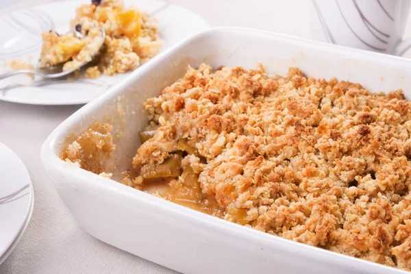 Apple crumble in a baking dish and a portion on a plate — Stock Photo, Image