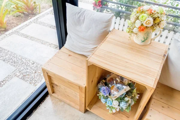 Ahşap masa ahşap tabure ve çiçek vazo ile iki yastık