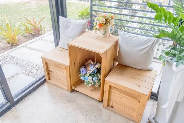 Dva polštáře na dřevěný stůl s dřevěnou stoličku a květinové vázy Stock Fotografie