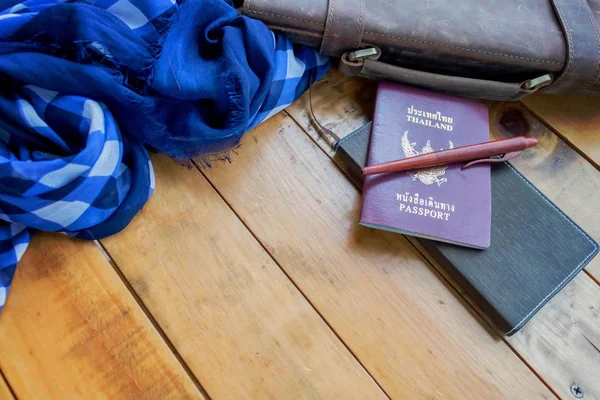 Deri kahverengi çanta pasaport ve defter ile lacivert ekose desenli eşarp.