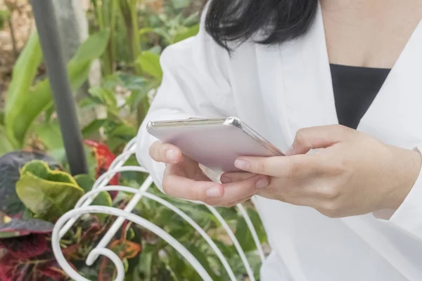 Beyaz bir cep telefonu sandalyede oturan bir kız tarafından kullanılan.