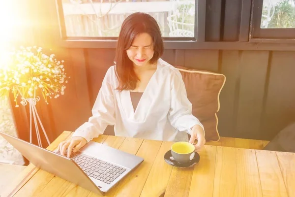 Beyaz gömlekli bir Asyalı kız defter siyah odasında ahşap masa üzerinde çalış.