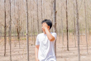 Tayland 'ın kuru ormanlarında beyaz pantalonlu Asyalı bir çocuk tek başına dikiliyor..