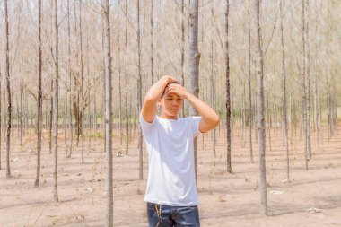 Tayland 'ın kuru ormanlarında beyaz pantalonlu Asyalı bir çocuk tek başına dikiliyor..