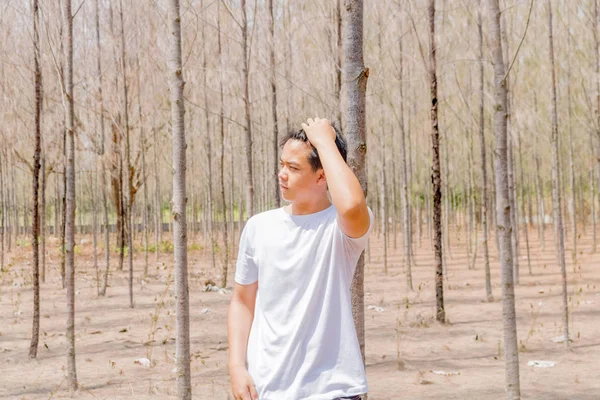 Tayland 'ın kuru ormanlarında beyaz pantalonlu Asyalı bir çocuk tek başına dikiliyor..