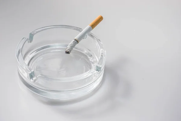 Overhead of burning cigarette in ashtray on white background — Stock Photo, Image