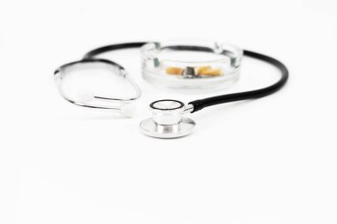 Küllükteki sigara ve steteskop tıbbi konsept için beyaz arka planda izole edilmiş ve seçici odaklanma ile çekiliyor.