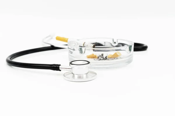 烟灰缸和听诊器中的香烟 在白色背景下隔离 用于医学概念和选择性聚焦拍摄 — 图库照片